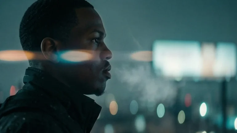 Cinematic AI press photo of a male musician looking out a window at night with teal and orange lighting.