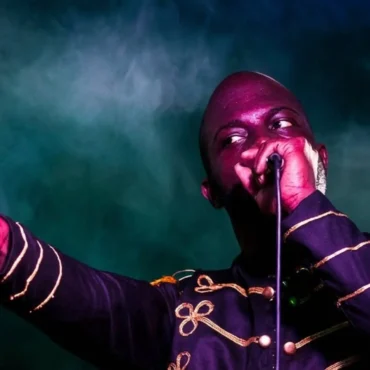 New Lewi performing live on stage with purple lighting.