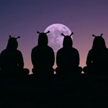 Four members of Space Cadets in alien costumes sitting on a rock silhouette against a purple moon and sunset.