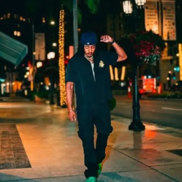 WAVVEEE walking on city street at night wearing neon green shoes.