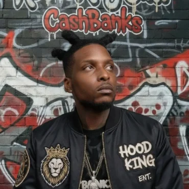 C.S.H. Banks wearing a black Hood King Ent bomber jacket against a graffiti wall.