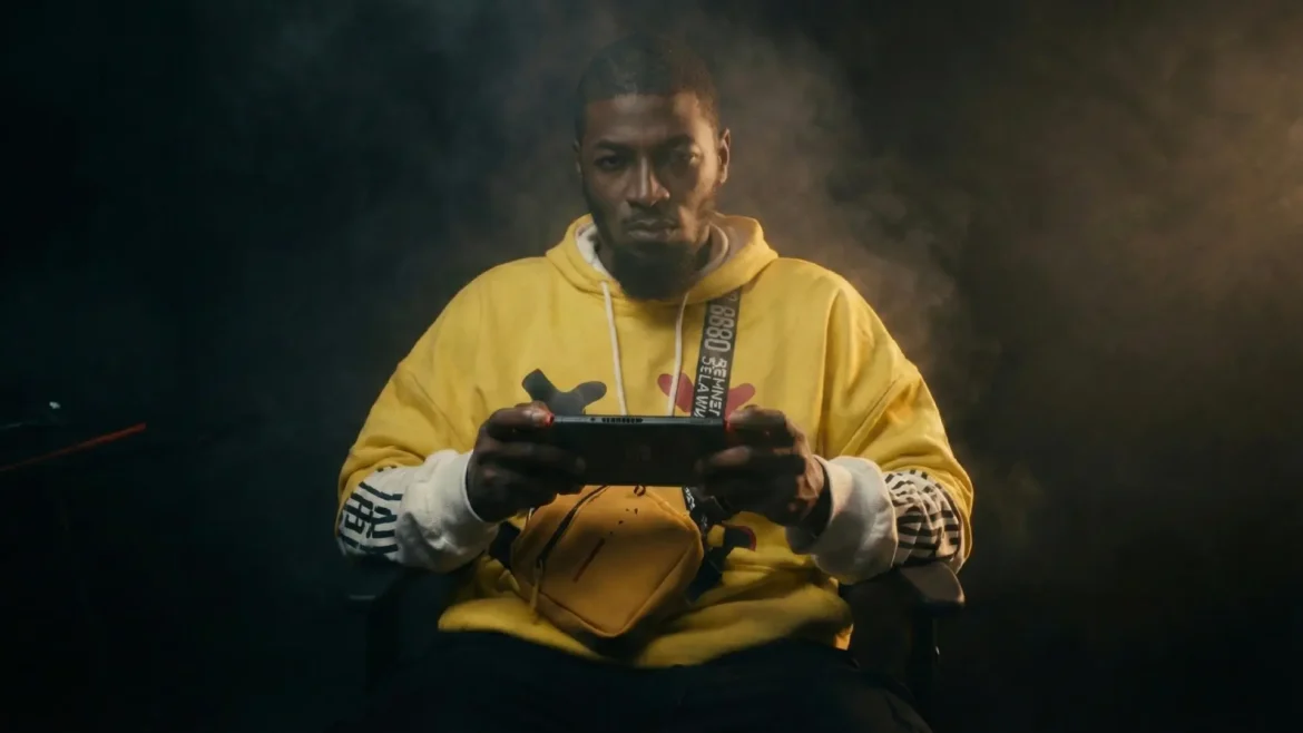 Musical artist Covay Fox wearing a yellow hoodie and holding a handheld gaming console.