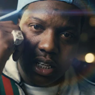 MacBoy Dero close-up wearing diamond grills and chains with a Gucci jacket.