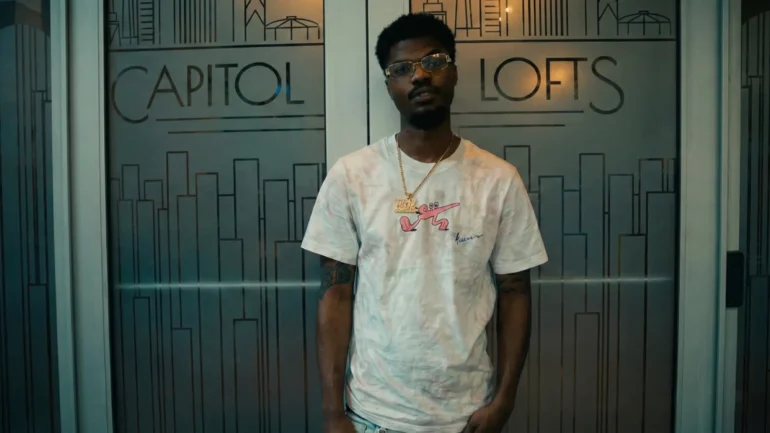 Richie Mike wearing a tie-dye shirt and glasses standing in front of Capitol Lofts glass doors.