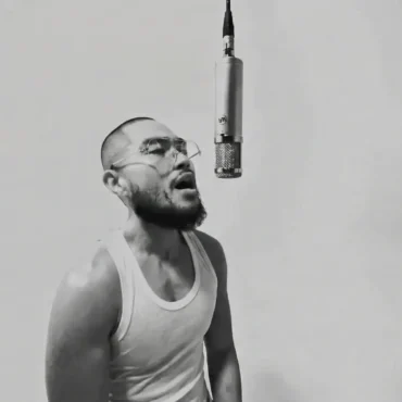 Russell Evan rapping into a hanging microphone in black and white.