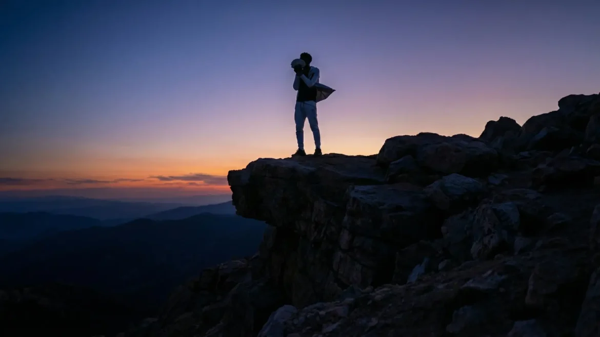 Silhouette of a man standing on a rocky mountain peak at sunset holding a stack of money.