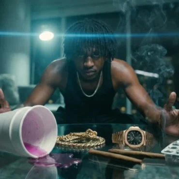 MBN Nito leaning over a glass table with a spilled styrofoam cup, pills, and a gold watch.