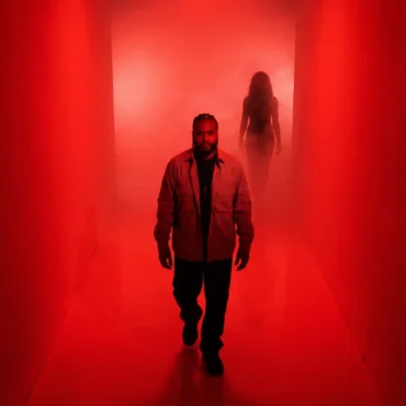 Rodney Hazard walking down a red-lit corridor with a woman's silhouette behind him.