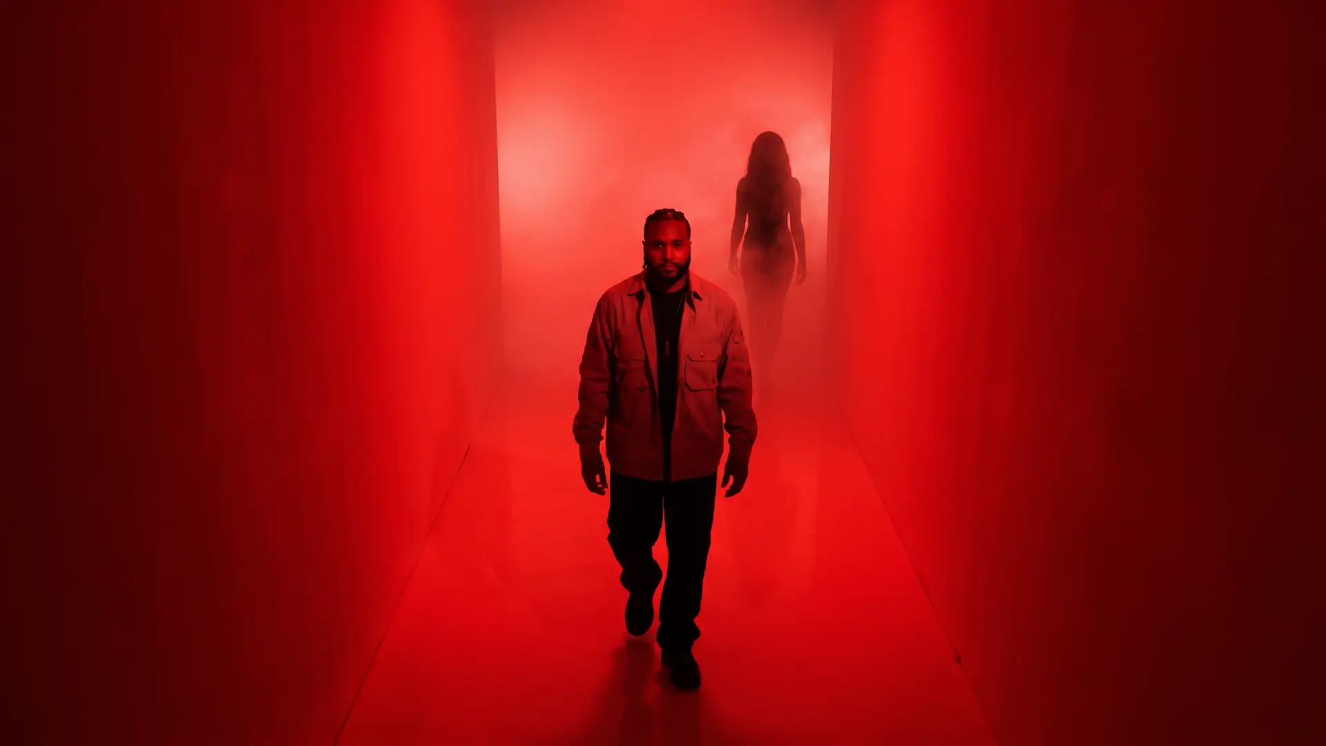 Rodney Hazard walking down a red-lit corridor with a woman's silhouette behind him.