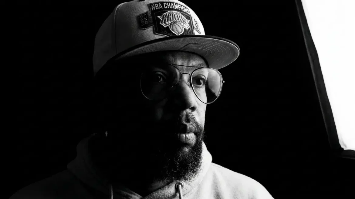 Black and white close-up portrait of Dezit wearing a New York Knicks cap and aviator glasses, promoting his single "Apply"
