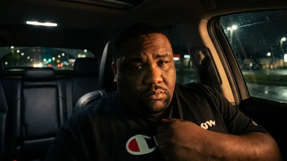 Unc Doe sits in the seat of a car at night, city lights and rain visible through the window behind him, gripping his shirt collar, "Heart Of Gold" by Unc Doe