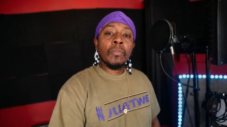 iLLACAT in purple headwrap and olive tee, studio portrait with vocal mic, "Like Dat" feat. Bookie